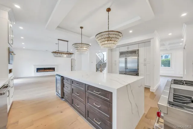 a large kitchen with stainless steel appliances kitchen island granite countertop a stove a sink a refrigerator and white cabinets with wooden floor