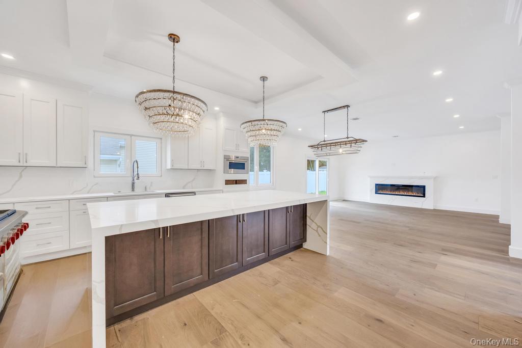 472 Farm Ranch Road East Bethpage, NY 11714 - Photo 5 of 40 Kitchen featuring a glass covered fireplace, plenty of natural light, recessed lighting, white cabinets, and a tray ceiling
