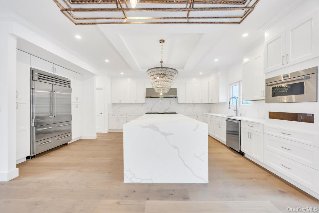 472 Farm Ranch Road East Bethpage, NY 11714 - Photo 6 of 40 a large kitchen with stainless steel appliances kitchen island granite countertop a stove a sink a refrigerator and white cabinets with wooden floor