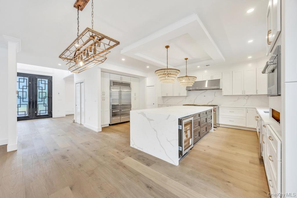 472 Farm Ranch Road East Bethpage, NY 11714 - Photo 8 of 40 Kitchen featuring a center island, backsplash, a chandelier, french doors, and light wood-style flooring