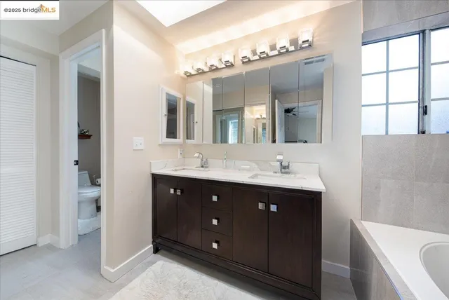 a bathroom with a double vanity sink mirror and bathtub