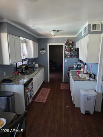 a kitchen with kitchen island granite countertop a sink and wooden floors
