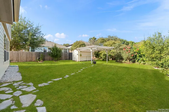 a view of a white house with a big yard plants and large trees