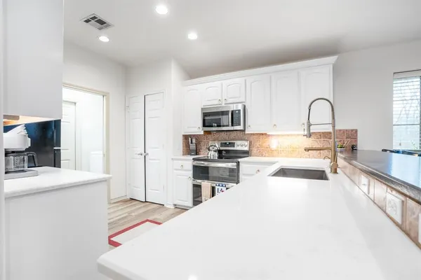 a large kitchen with stainless steel appliances granite countertop a stove a sink dishwasher and a refrigerator with wooden floor