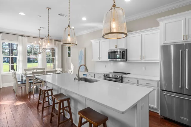 a kitchen with stainless steel appliances a table chairs in it and wooden floors