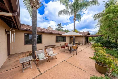 a view of a patio with a table and chairs under an umbrella with potted plants