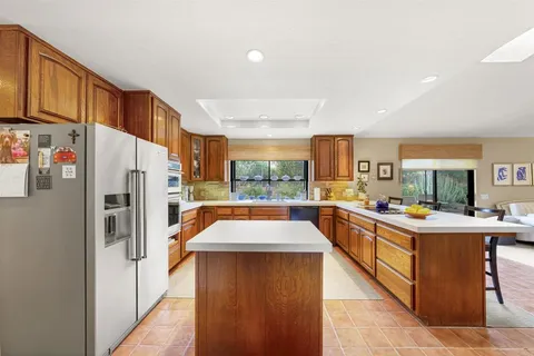 a kitchen with stainless steel appliances a refrigerator a sink a stove top oven a dining table and chairs