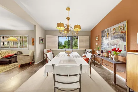 a very nice looking dining room with a large window table and chairs