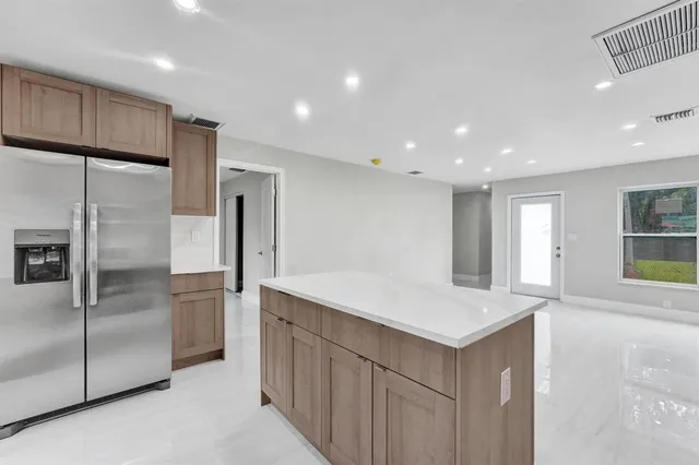 a kitchen with kitchen island a counter top space cabinets and stainless steel appliances