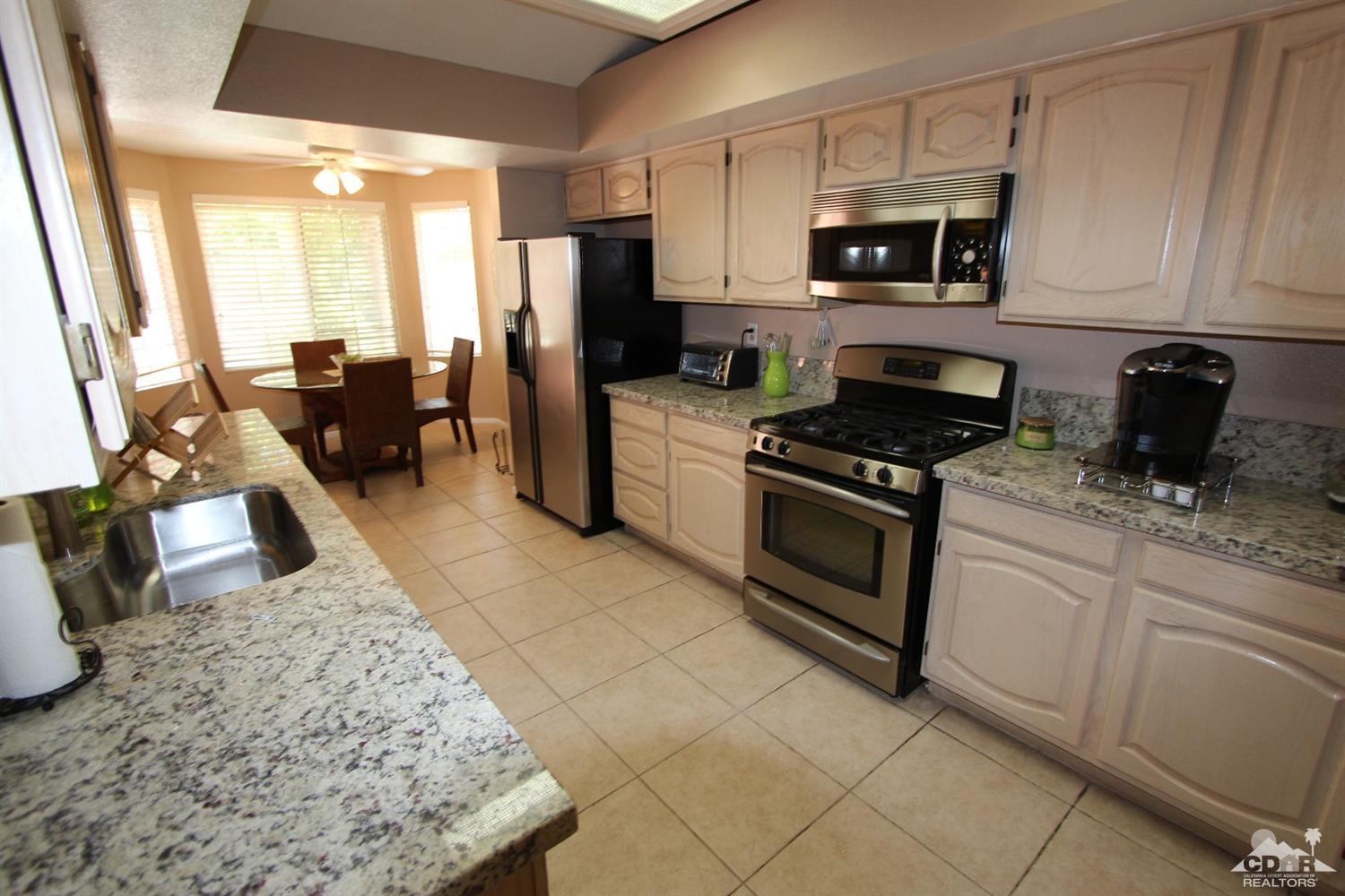 68335 Risueno Road Cathedral City, CA 92234 - Photo 8 of 32 a kitchen with stainless steel appliances granite countertop a stove top oven a sink a counter space and cabinets