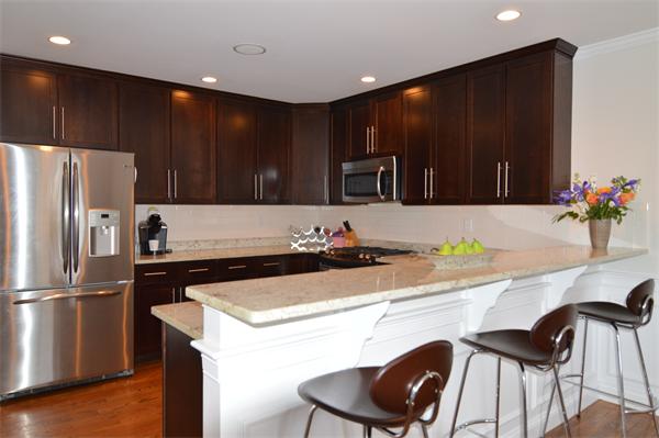 115 Booth Street, Unit 115 Needham, MA 02494 - Photo 2 of 15 a kitchen with wooden cabinets a refrigerator and a stove top oven