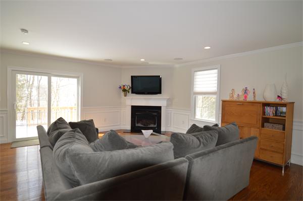 115 Booth Street, Unit 115 Needham, MA 02494 - Photo 4 of 15 a living room with furniture a flat screen tv and a fireplace
