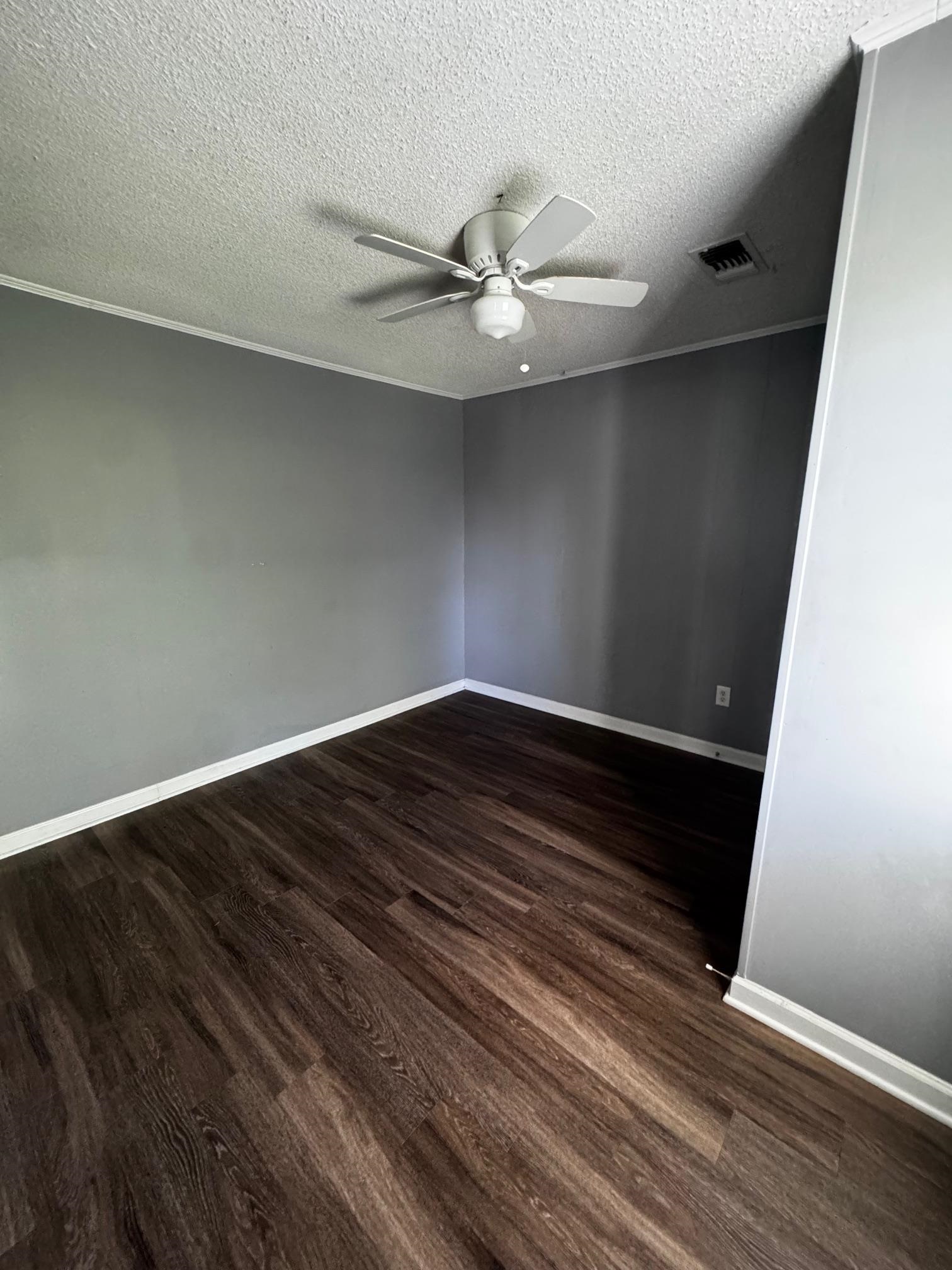 1112 Shoaf Road Covington, TN 38019 - Photo 13 of 17 Unfurnished room featuring dark wood-style flooring, a textured ceiling, crown molding, and a ceiling fan