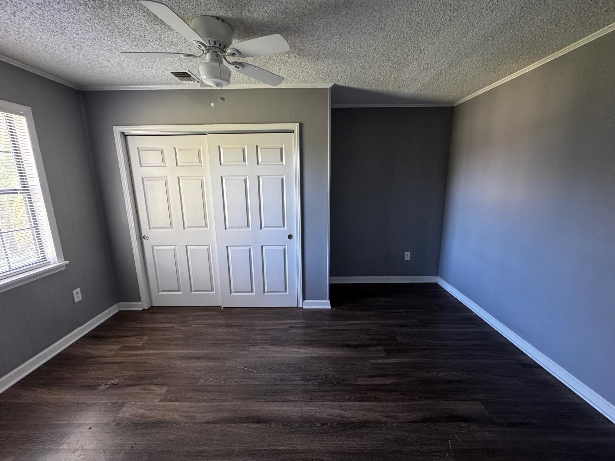 1112 Shoaf Road Covington, TN 38019 - Photo 14 of 17 Unfurnished bedroom with ornamental molding, dark wood finished floors, ceiling fan, a closet, and a textured ceiling