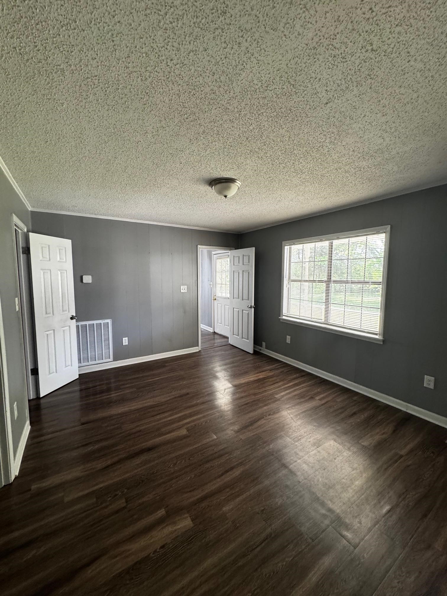 1112 Shoaf Road Covington, TN 38019 - Photo 6 of 17 Unfurnished bedroom with a textured ceiling and dark wood-style flooring