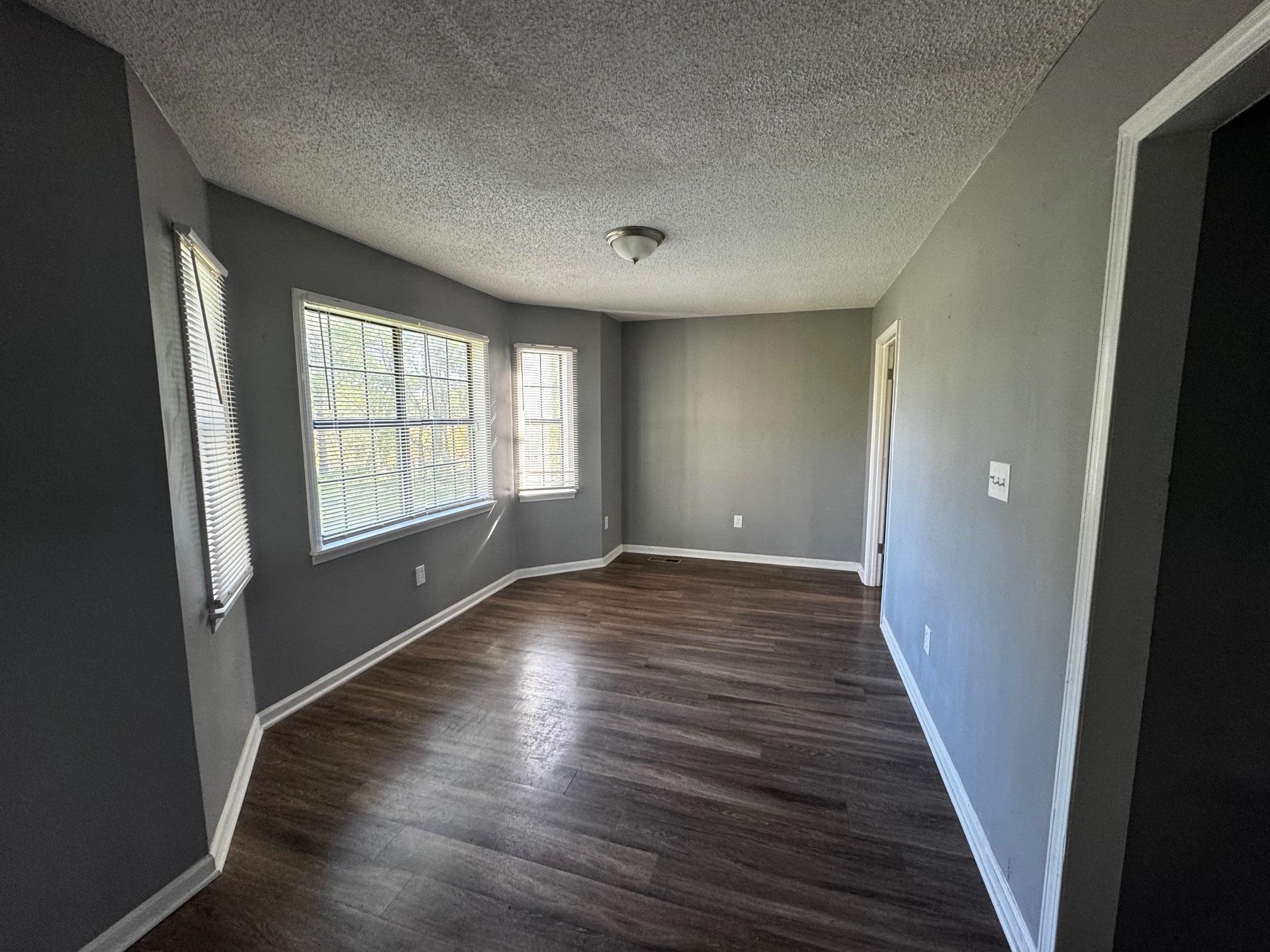 1112 Shoaf Road Covington, TN 38019 - Photo 9 of 17 Empty room featuring dark wood-style flooring and a textured ceiling