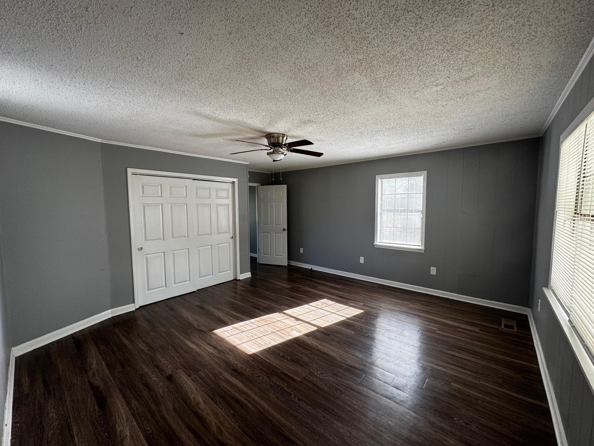 1112 Shoaf Road Covington, TN 38019 - Photo 10 of 17 Unfurnished bedroom featuring a closet, dark wood finished floors, a ceiling fan, a textured ceiling, and ornamental molding