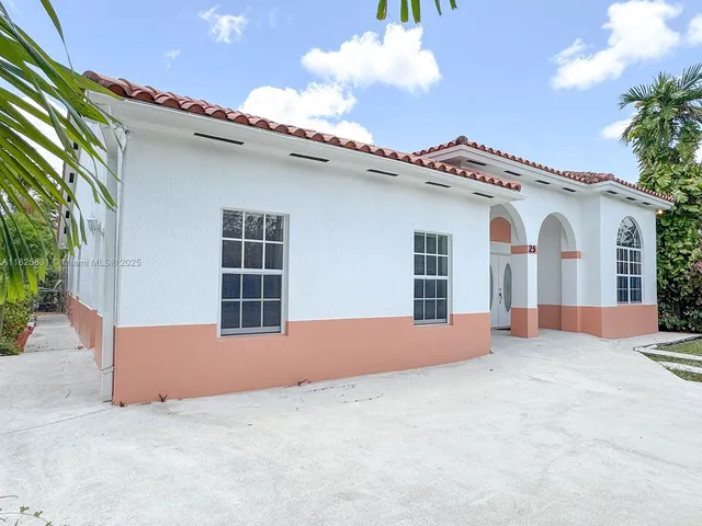 a view of a white house with a yard and potted plants
