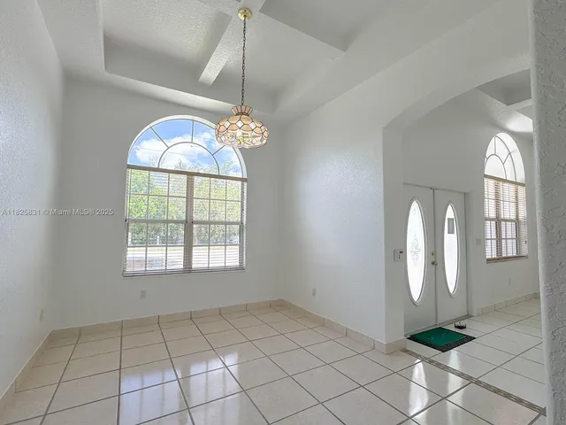 an empty room with windows and chandelier fan