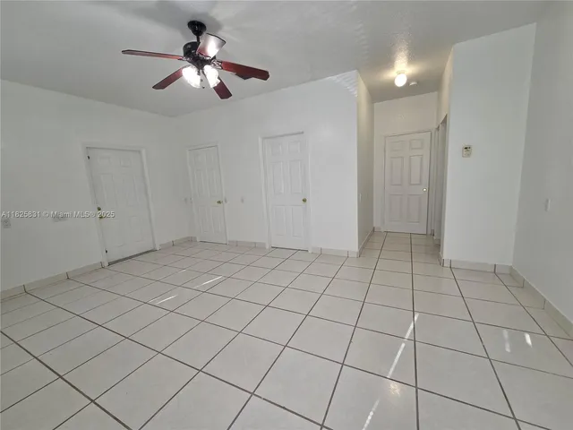 a view of an empty room and chandelier fan