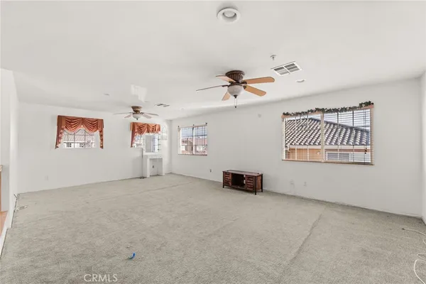 an empty room with windows and fan