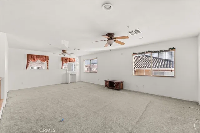 an empty room with windows and fan