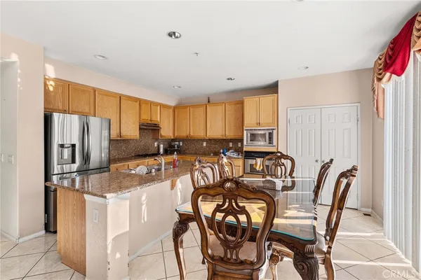 a kitchen with stainless steel appliances granite countertop a stove a refrigerator a table and chairs