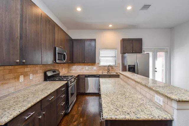a kitchen with stainless steel appliances granite countertop a sink stove microwave and refrigerator