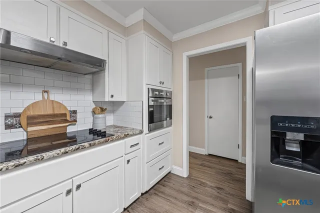 a kitchen with granite countertop white cabinets and stainless steel appliances