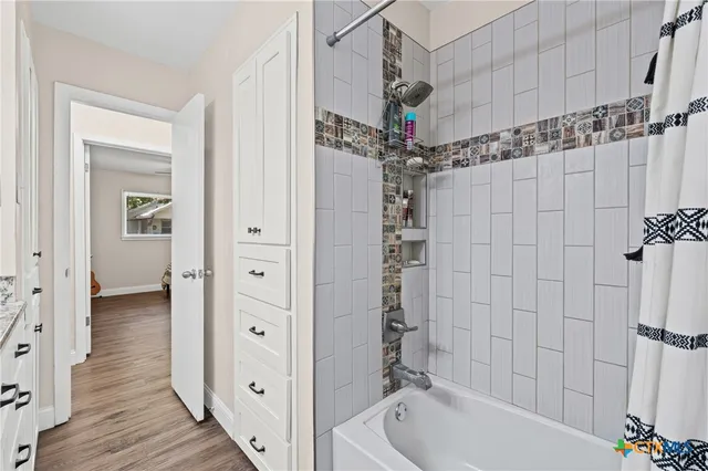 a bathroom with a tub shower vanity and a sink
