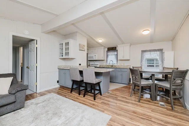 a living room with stainless steel appliances kitchen island granite countertop furniture and wooden floor