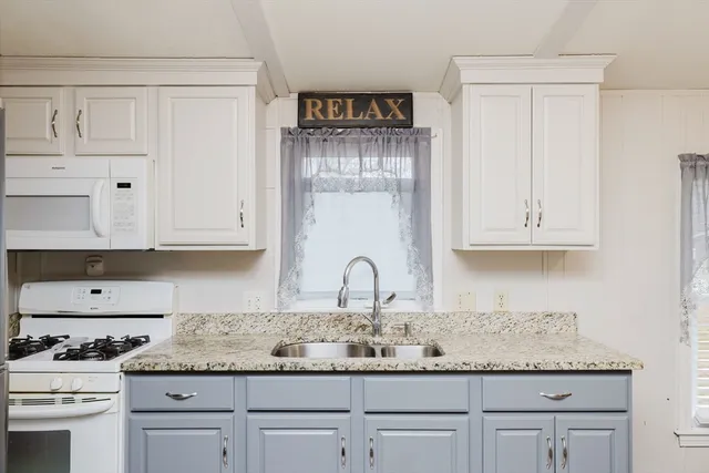 a kitchen with granite countertop white cabinets and white appliances