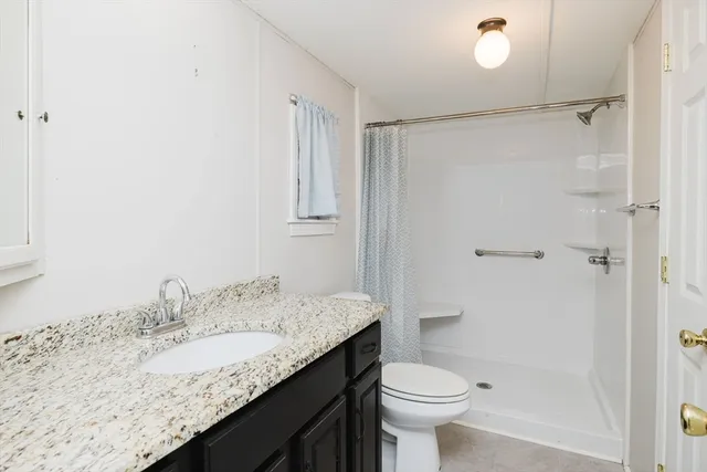 a bathroom with a granite countertop sink toilet and shower
