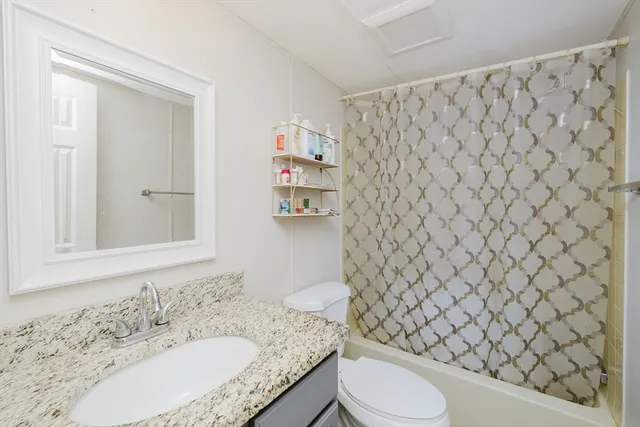 a bathroom with a granite countertop toilet and a sink