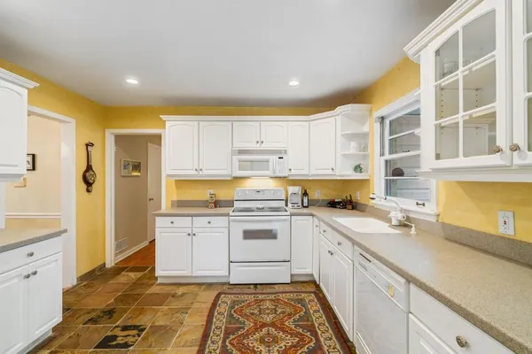 a kitchen with granite countertop white cabinets and white appliances
