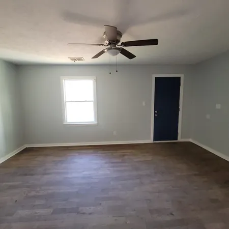 an empty room with wooden floor ceiling fan and windows