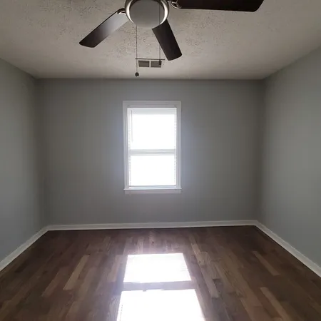 an empty room with wooden floor cabinets and windows