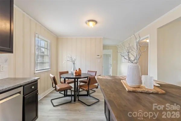 a open kitchen with stainless steel appliances granite countertop a stove top oven a sink dishwasher a dining table and chairs with wooden floor
