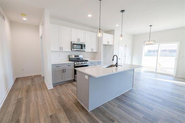 14200 Prairie Commons Lane South Beloit, IL 61080 - Photo 5 of 13 a large kitchen with stainless steel appliances a large counter top a sink a stove and a wooden floors