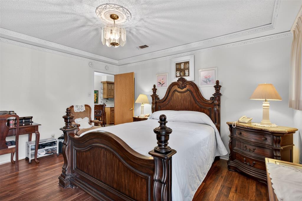 6010 Hunters View Lane Dallas, TX 75232 - Photo 22 of 28 Bedroom featuring rich wood-finish flooring, intricate ceiling molding, and a decorative ceiling light fixture