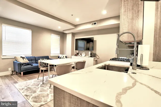 a living room with stainless steel appliances kitchen island granite countertop furniture and a large window