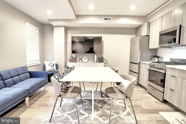 a living room with furniture a flat screen tv and kitchen view