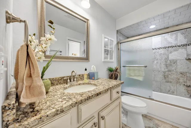 a bathroom with a granite countertop sink toilet and shower