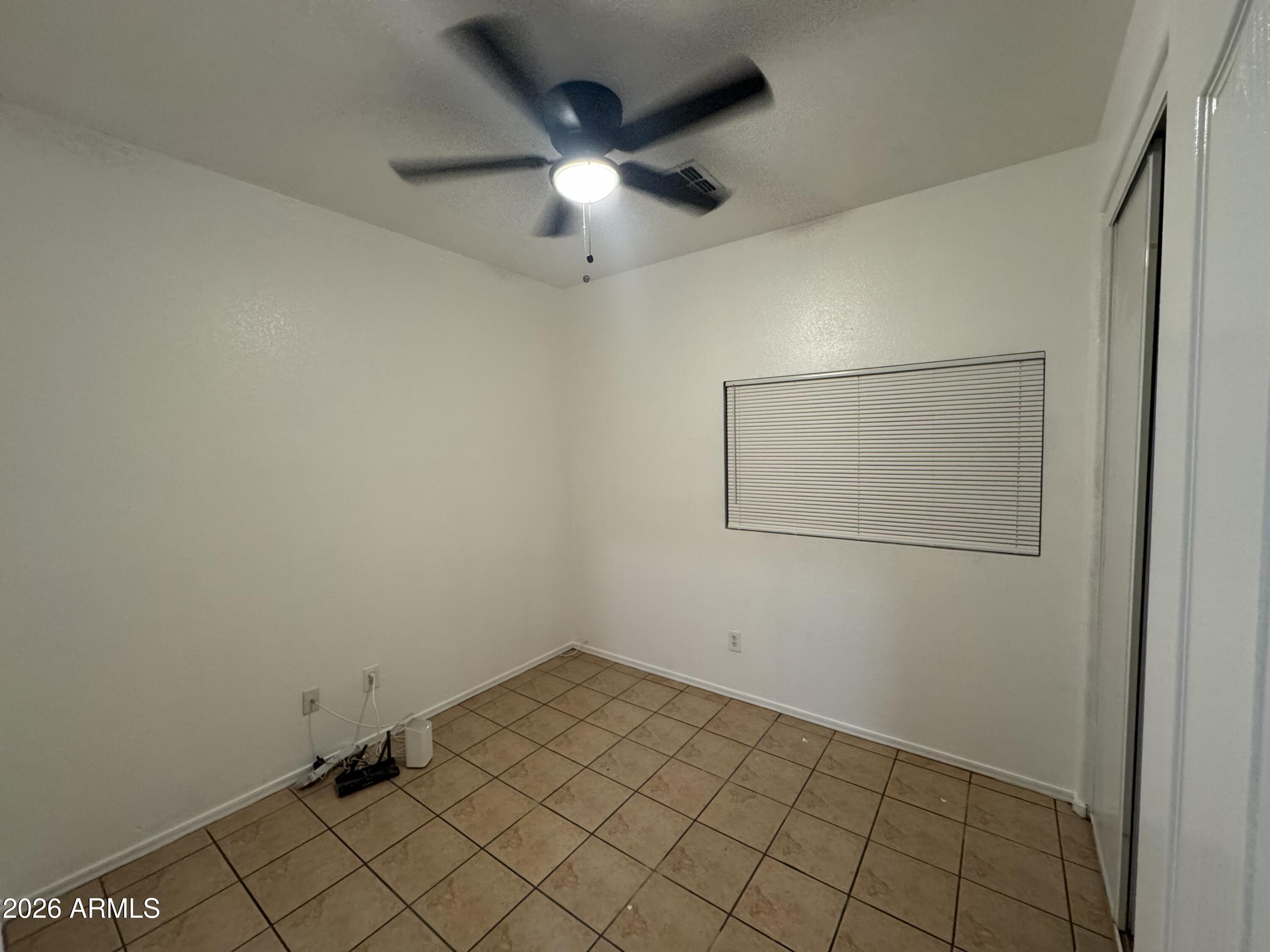 9730 West Payson Road Tolleson, AZ 85353 - Photo 47 of 57 an empty room with a ceiling fan and carpet