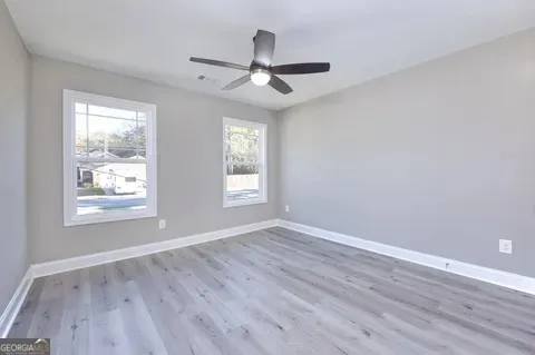 an empty room with wooden floor and ceiling fan