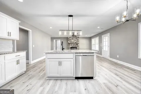a large kitchen with granite countertop a large center island a sink stainless steel appliances and cabinets