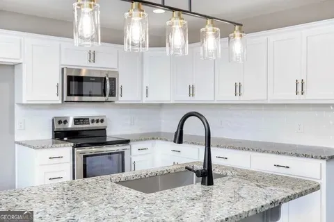 a kitchen with stainless steel appliances granite countertop a sink a stove and microwave