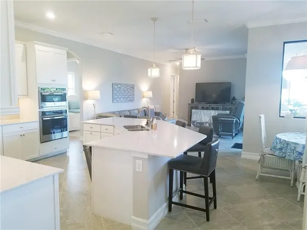 a open kitchen with stainless steel appliances kitchen island a table chairs in it and a wooden floors