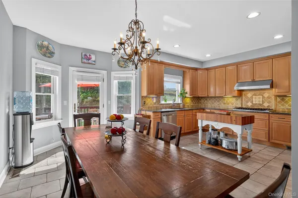 a open dining room with stainless steel appliances granite countertop a stove top oven a dining table and chairs with wooden floor