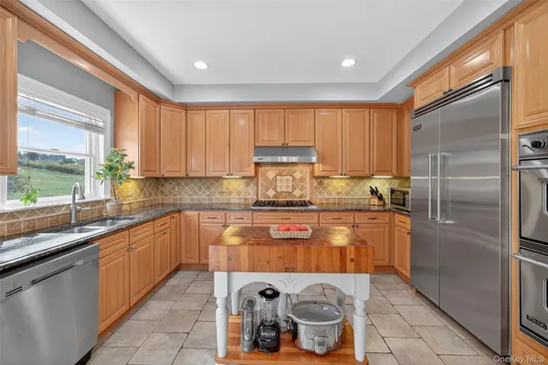 a kitchen with stainless steel appliances granite countertop a refrigerator a stove a sink and a window